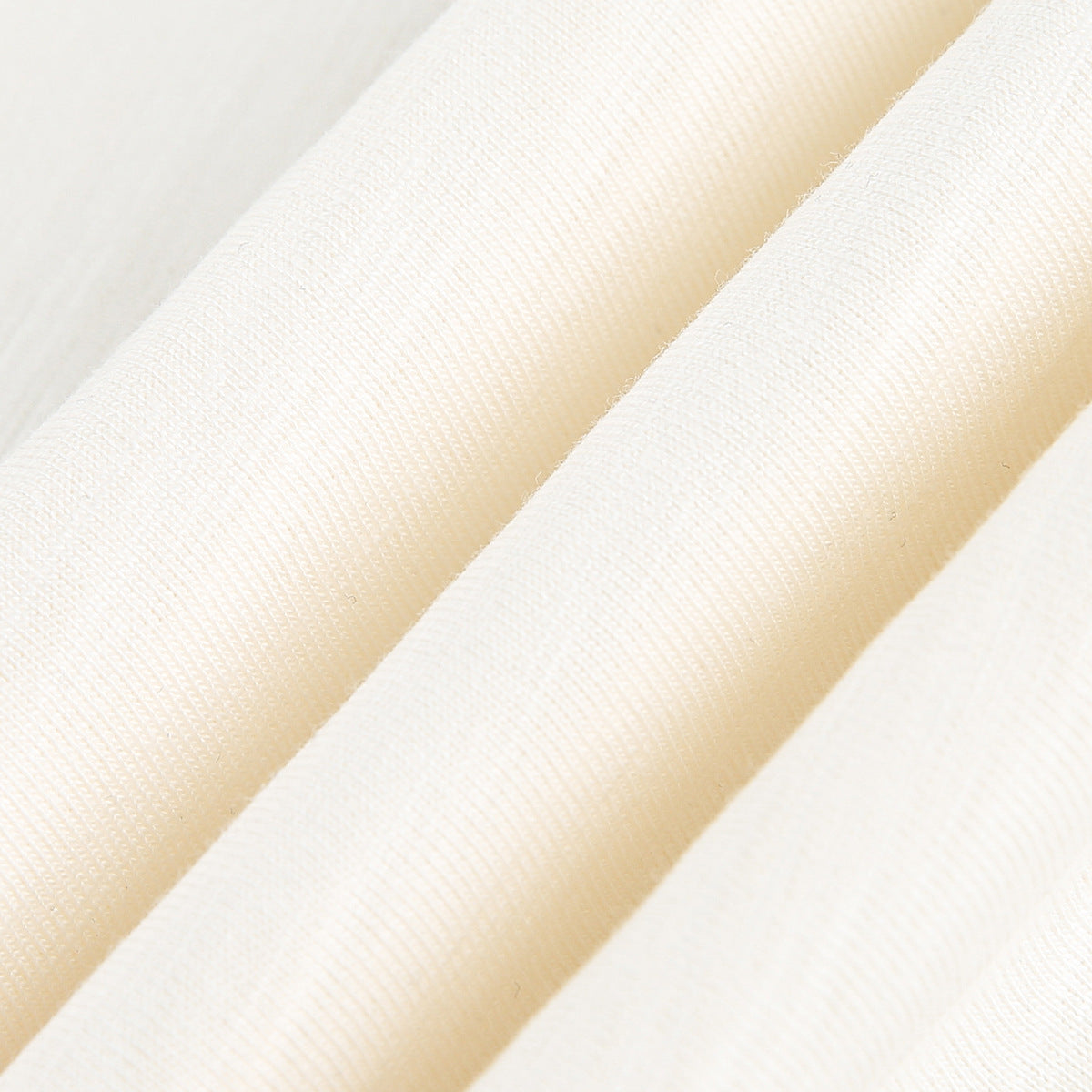 Macro view of the ivory T-shirt fabric, showing its knit texture and folded surface.
