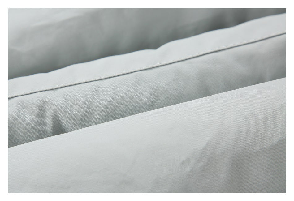 Close-up of stitched seams and layered light gray garment fabric.