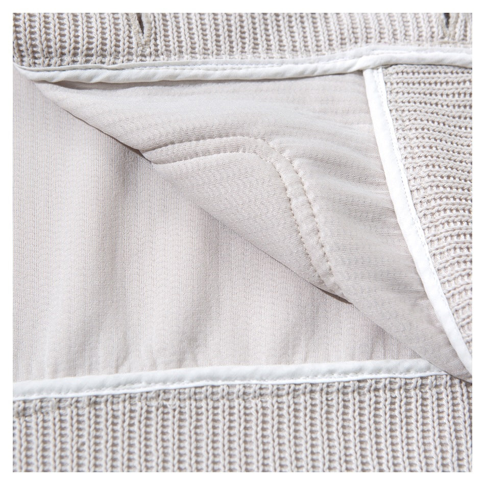 Close-up of the light beige cardigan's inside fabric and finished seams around an opening.