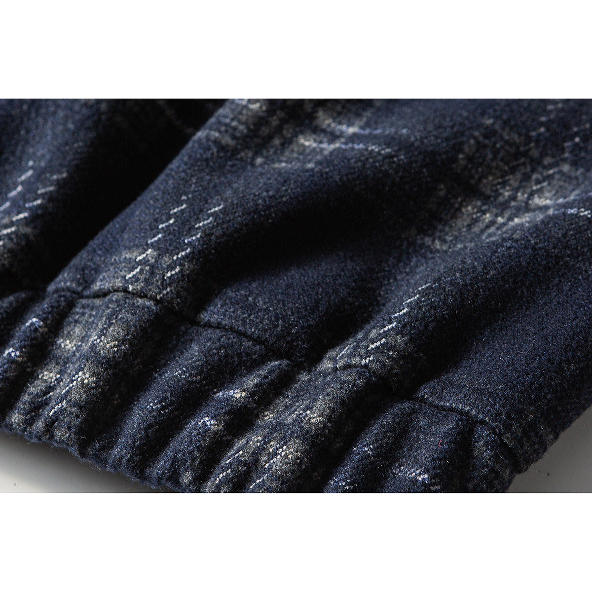 Close-up of gathered elastic edging and the dark navy jacket's gray plaid pattern.