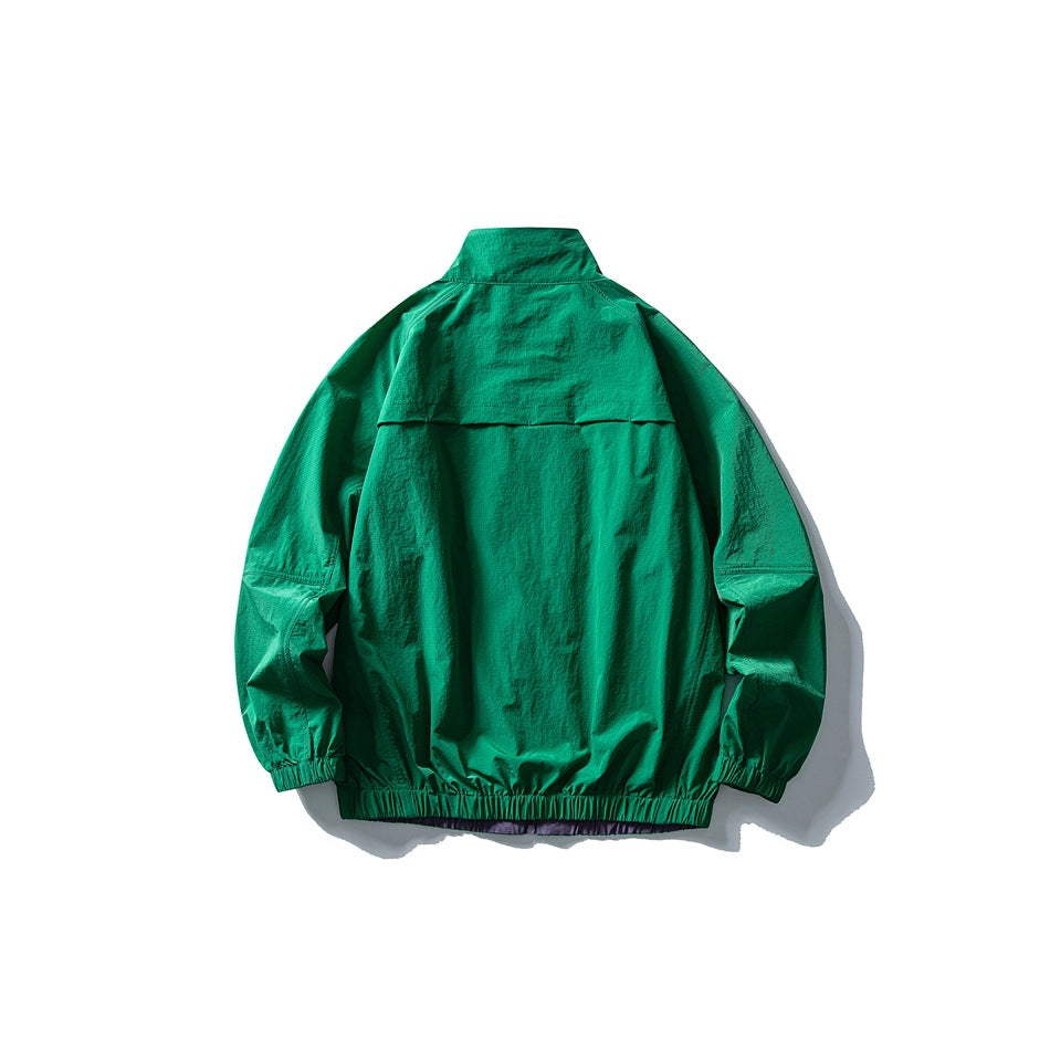 Back view of an emerald green jacket with a high collar, back vent flap, and elastic cuffs and hem; purple shows below the