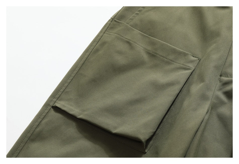 Close-up of an olive-green trouser leg with a large stitched cargo pocket.