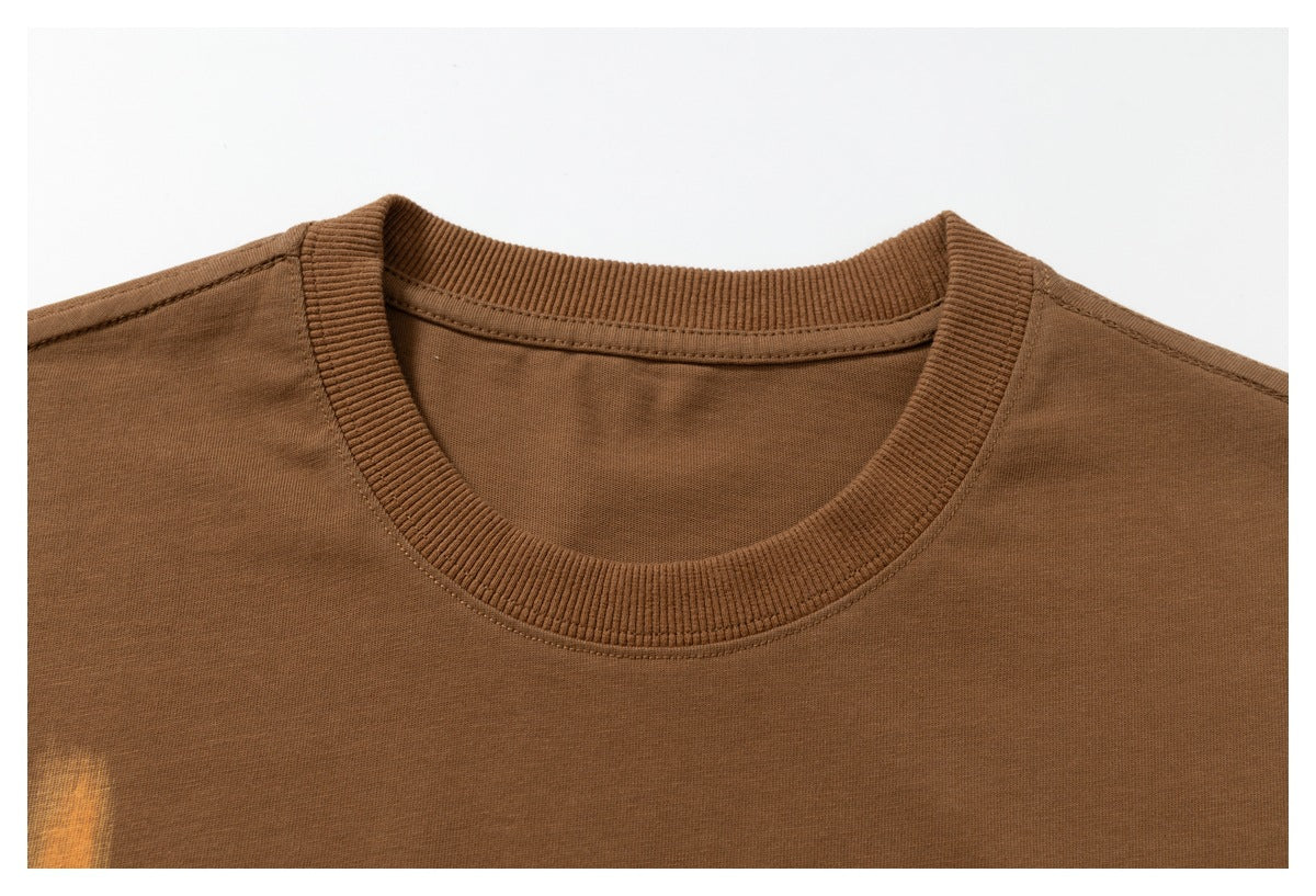 Close-up of the ribbed crew neckline and shoulder stitching on a brown T-shirt.