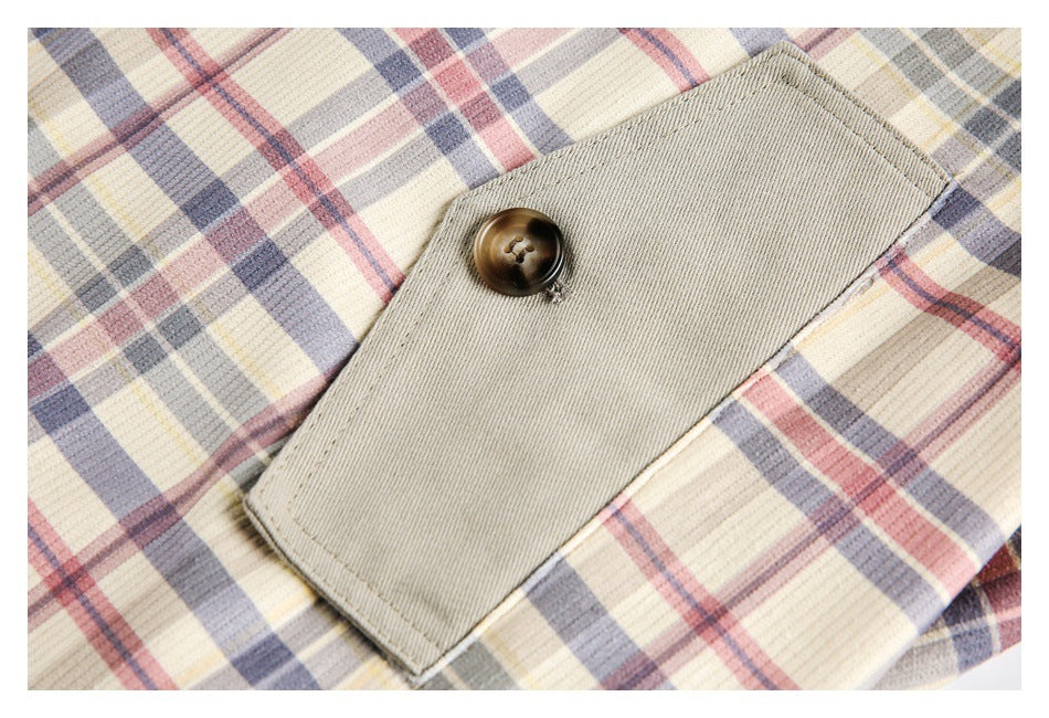 Close-up of a rectangular khaki pocket flap with a dark button on cream plaid fabric.