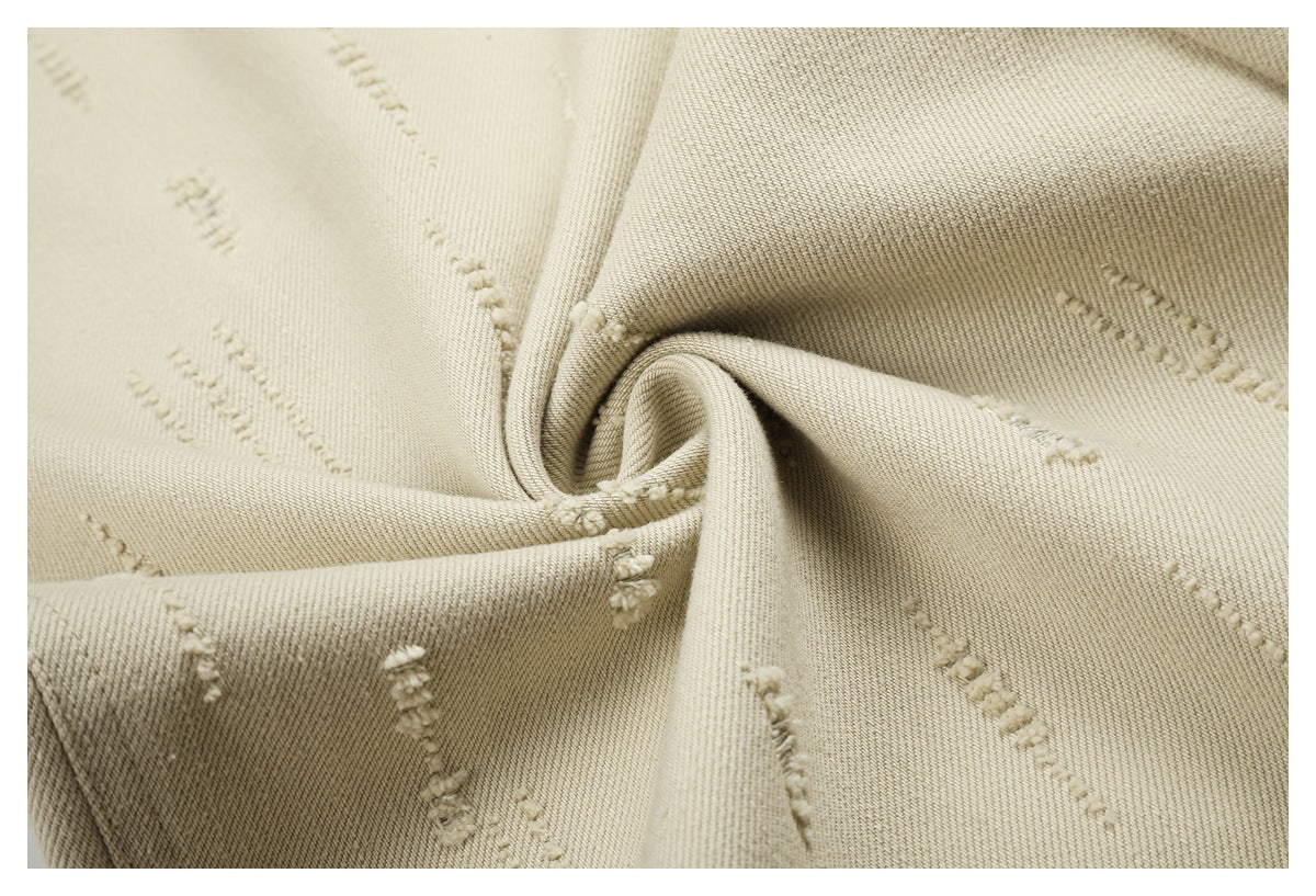 Macro view of cream trouser fabric showing its diagonal weave and raised stitched marks.