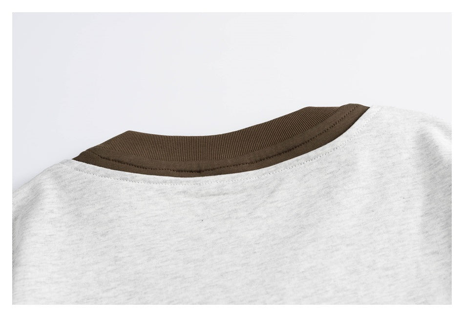 Close-up of a light gray heather shirt neckline with dark brown ribbed trim.