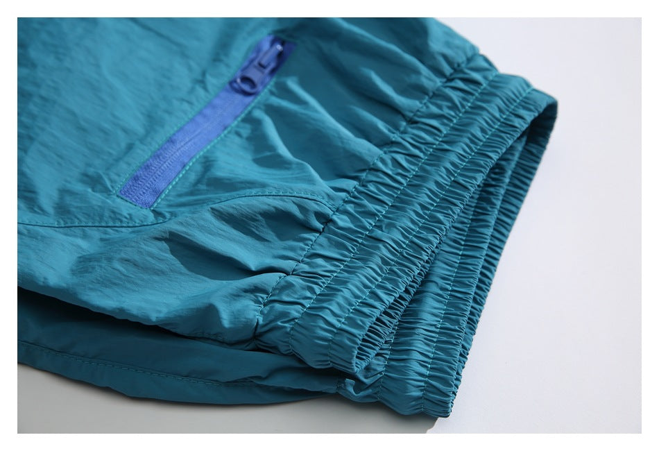 Close-up of the teal shorts’ elastic waistband and blue zippered pocket.