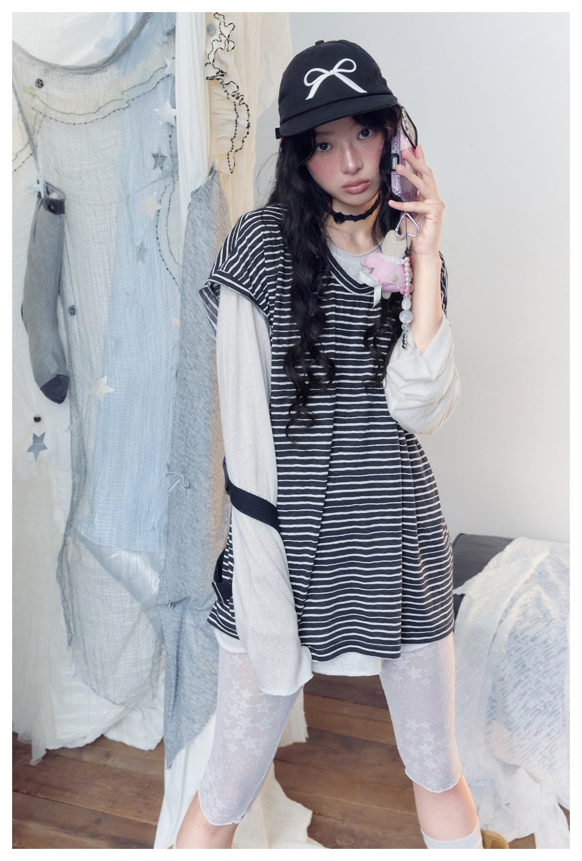 Model wearing a loose black-and-white striped top over a light long-sleeve shirt, shown with star-print leggings.