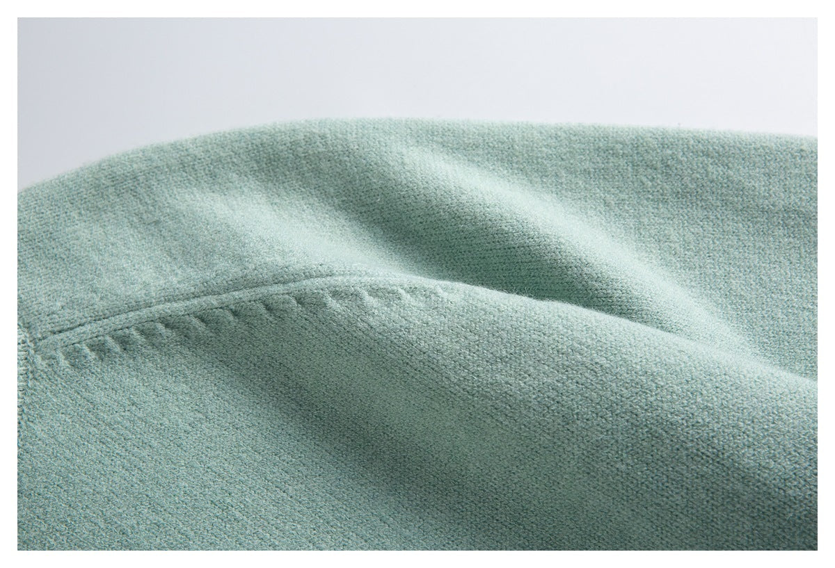 Close-up of pale mint-green knit fabric showing a raised seam and soft folds.
