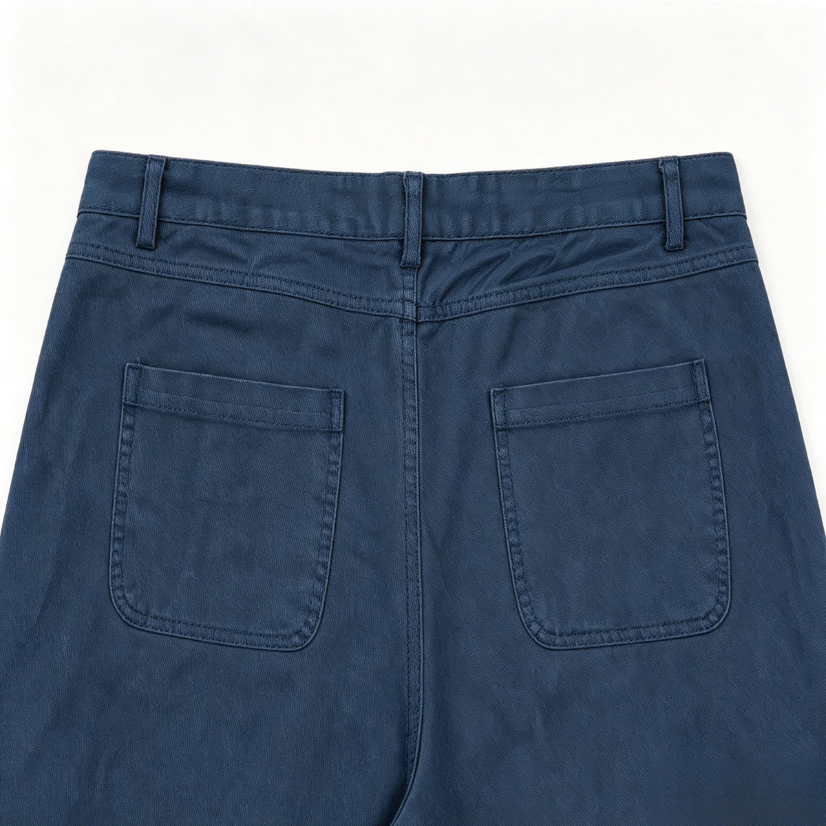 Close-up of the back of blue trousers, showing the waistband, belt loops, and two patch pockets.