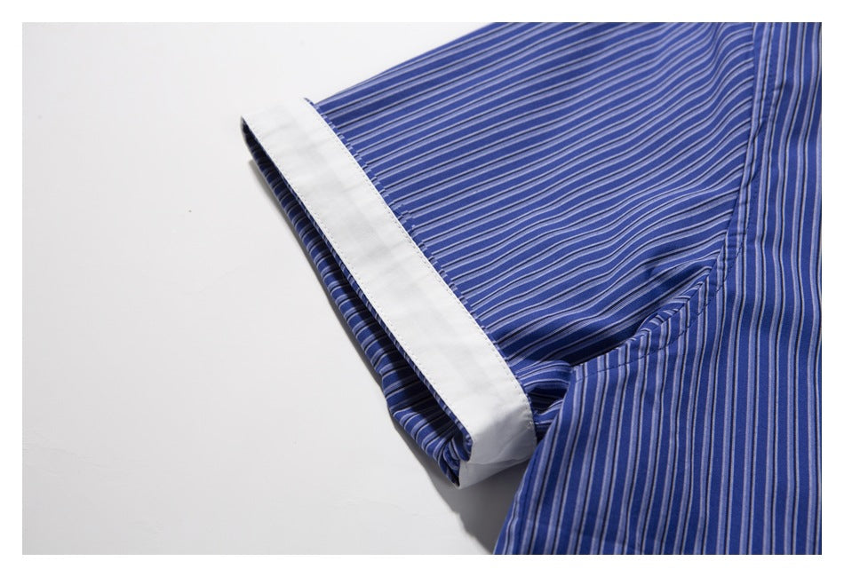 Close-up of a blue striped shirt sleeve with a wide white cuff turned outward.