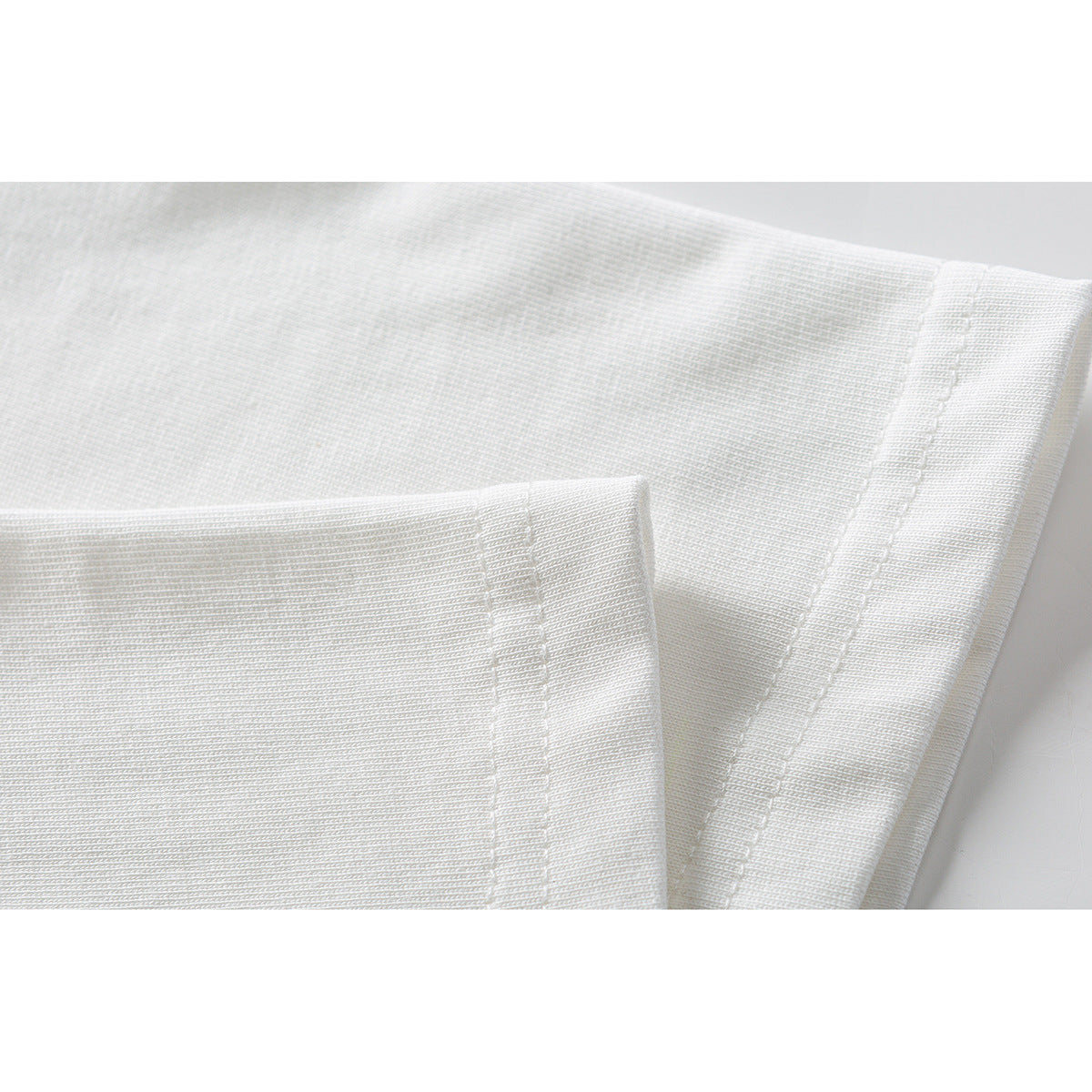 Close-up of white T-shirt fabric and double-stitched sleeve hems.