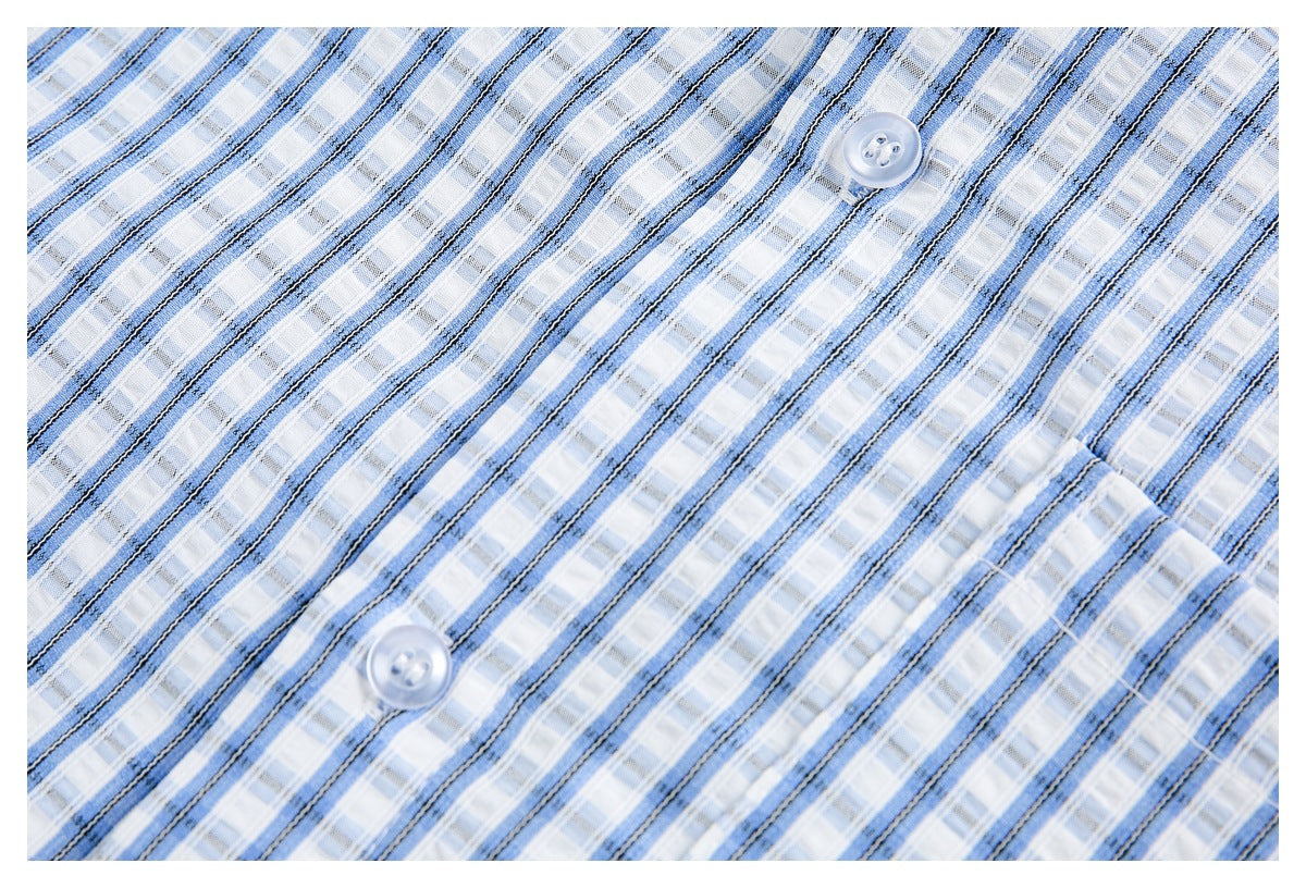 Blue and white plaid shirt fabric close-up with dark stripe accents and two translucent buttons.