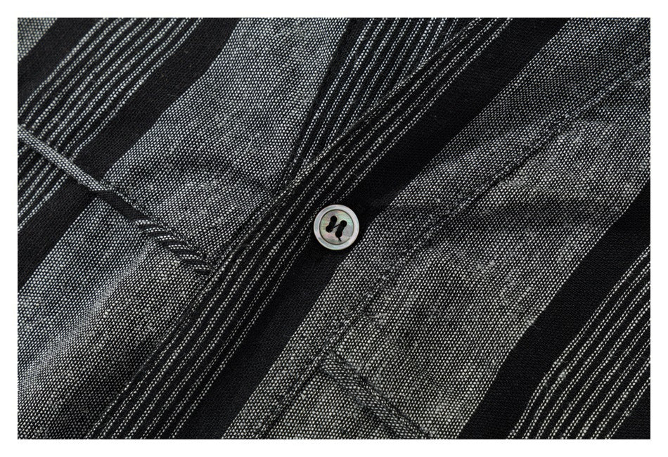 Close-up of the black and gray striped shirt fabric, button, and placket stitching.