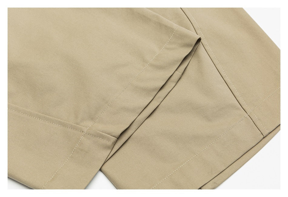 Close-up of beige trouser legs showing wide hems, seams and overlapping folds.