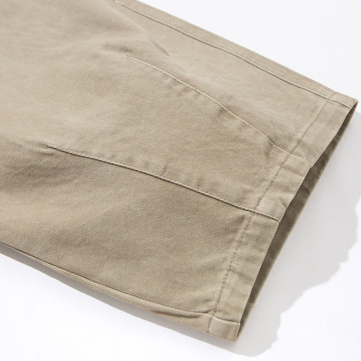 Close-up of a beige trouser leg showing its stitched panel and hem.