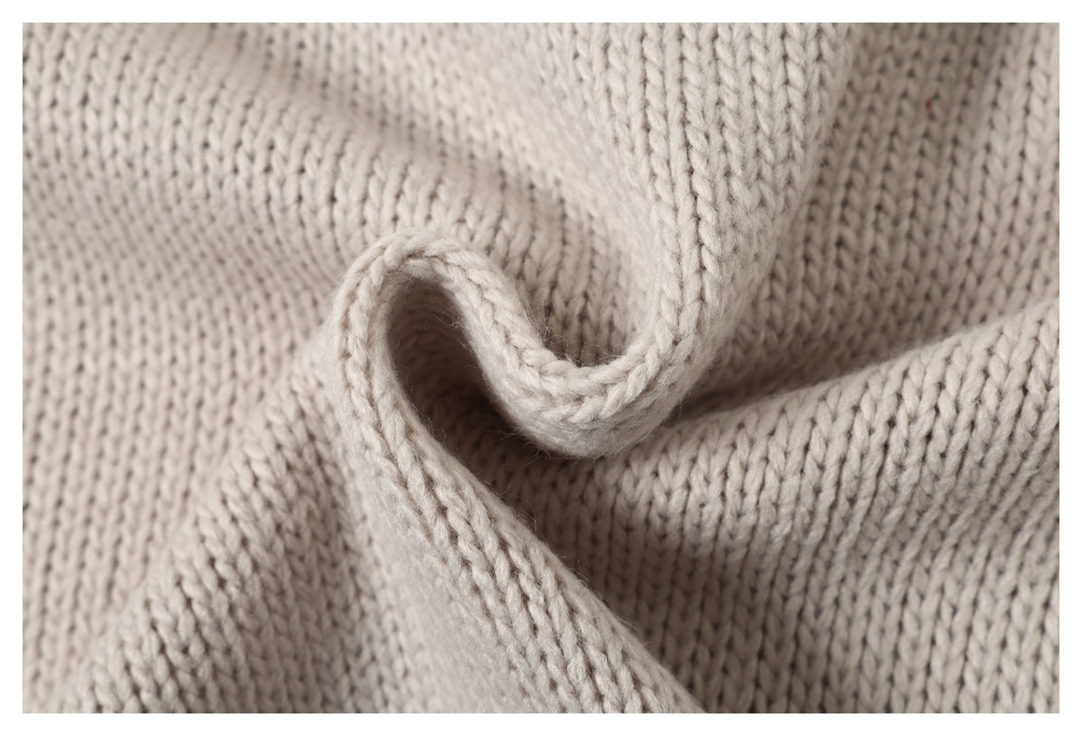 Close-up of cream knit fabric curled into a fold, showing its edge and stitching.
