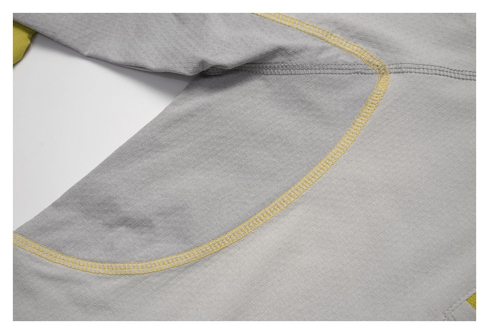 Close-up of curved yellow overlock stitching and gray fabric panels on a top.