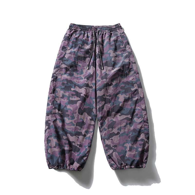 Purple camouflage wide-leg drawstring pants with gathered hems, flat front view