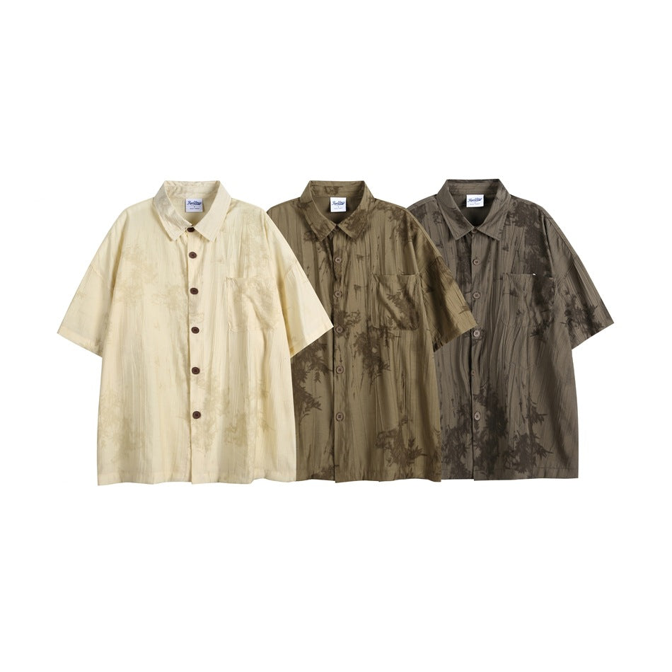Three short-sleeve button-up shirts shown together in ivory, olive, and dark brown patterned colorways.