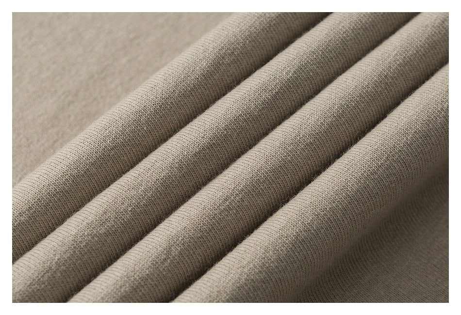 Close-up of taupe-gray knit fabric arranged in soft folds, showing its fine textured surface.