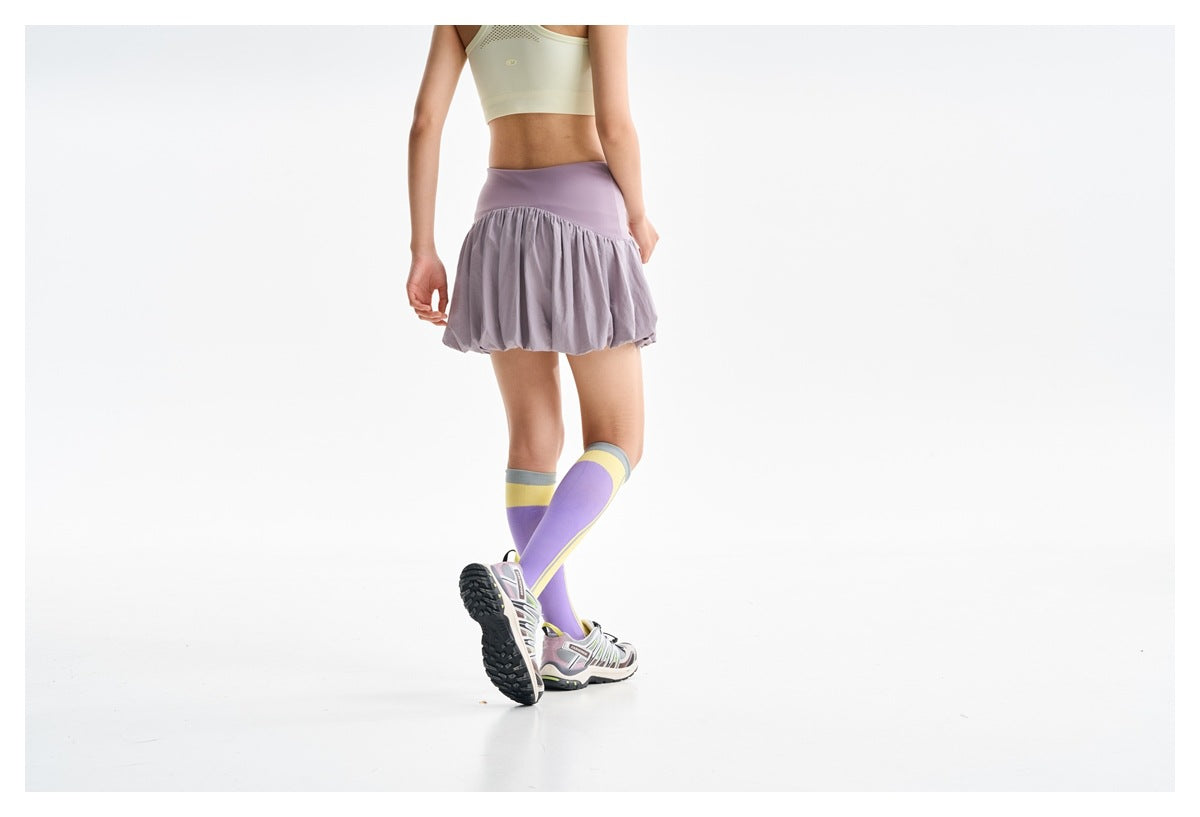 Rear view of a model wearing a lilac bubble-hem skirt with a pale yellow crop tank.