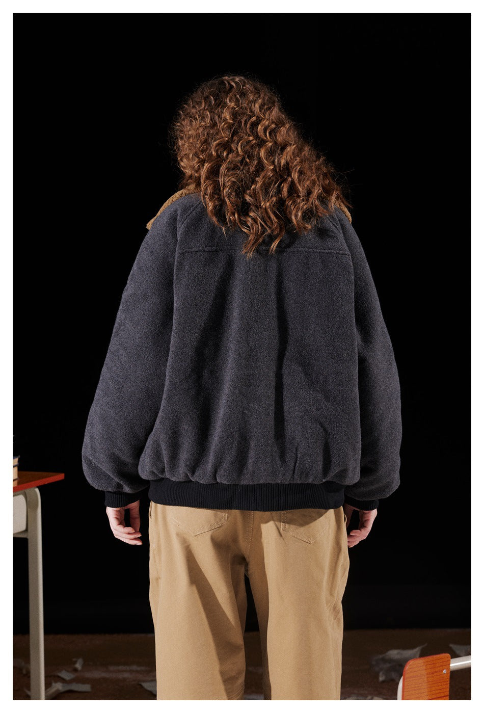Back view of a model wearing a charcoal jacket with a tan collar and black ribbed hem and cuffs.