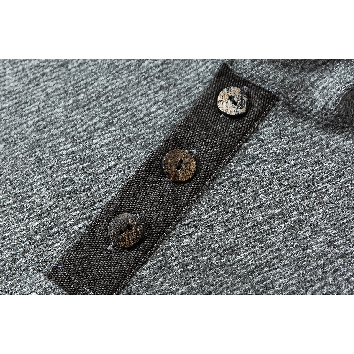 Close-up of three mottled buttons on a dark placket against gray textured knit.