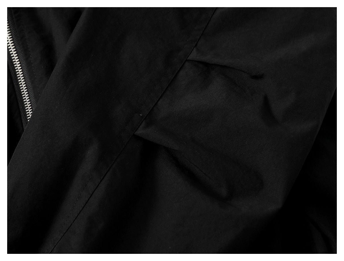 Close-up of a flap pocket on the black jacket sleeve, with part of the front zipper visible.