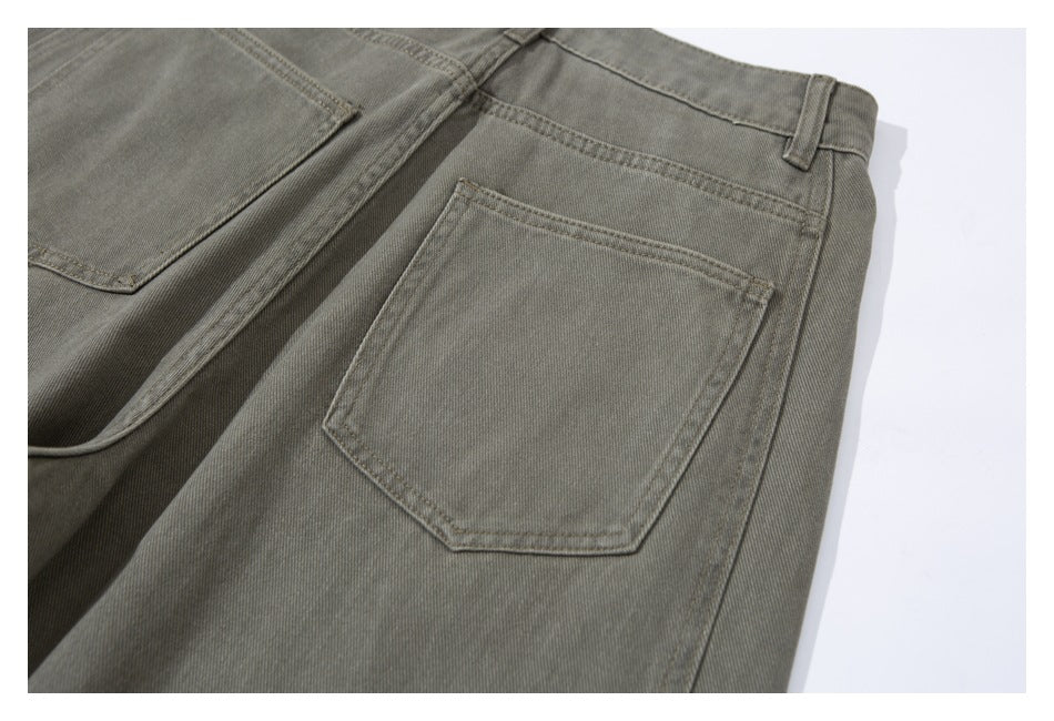 Close-up of olive-gray pants showing the back waistband, belt loop, and stitched patch pocket.