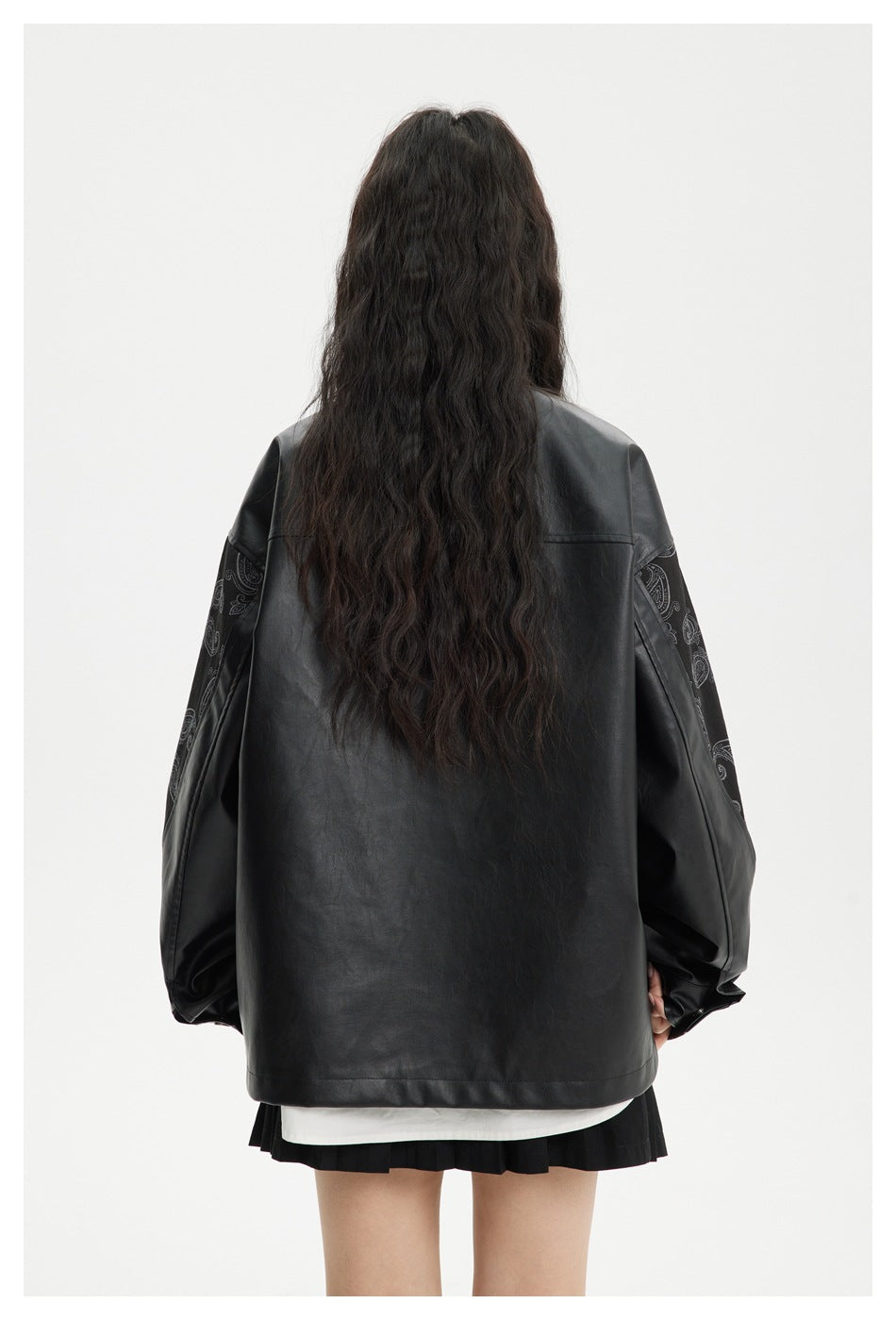 Back view of a model wearing an oversized black jacket with paisley-patterned sleeves.