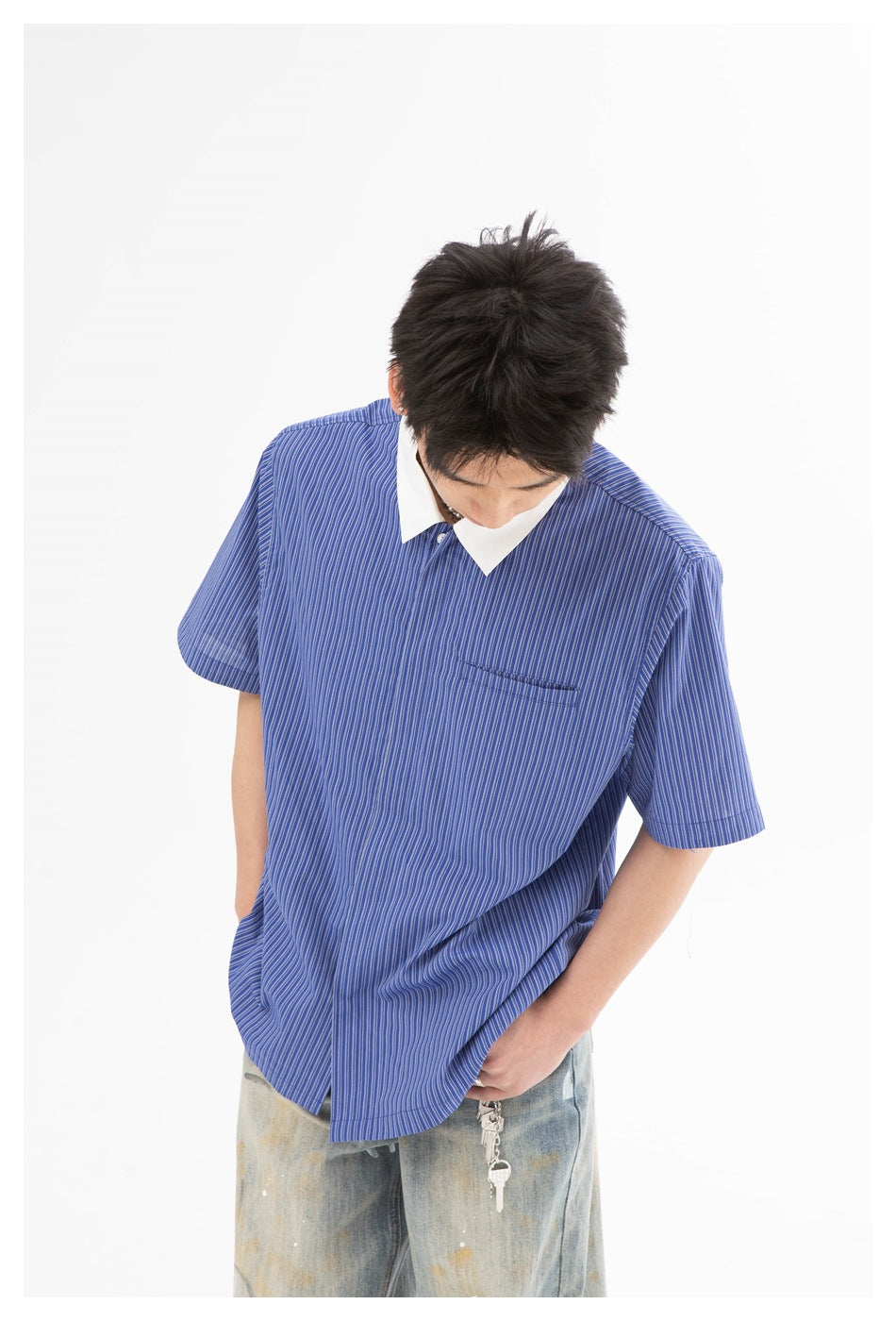 Close view of a model looking down in a blue pinstriped shirt with a white collar and chest pocket.