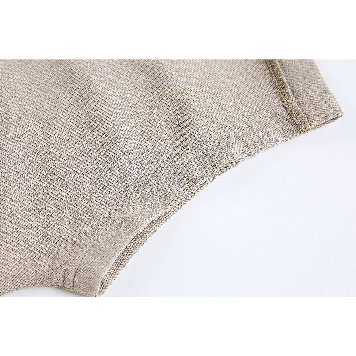 Close-up of beige shirt fabric and stitching at a short sleeve edge and side seam.