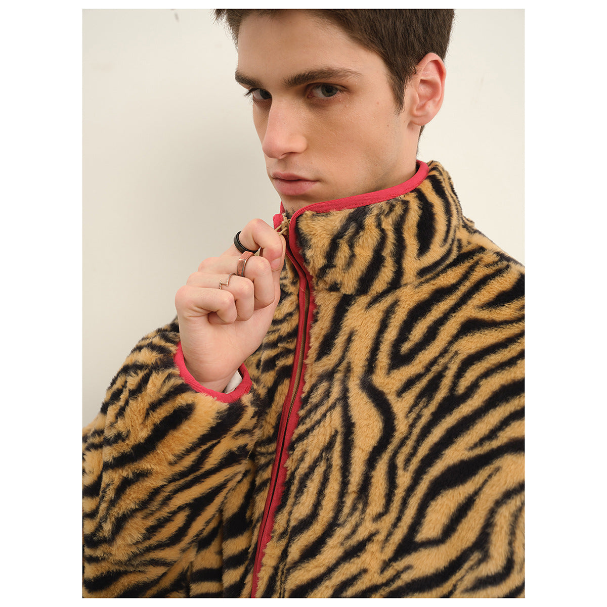Close-up of a man wearing a tan-and-black tiger-stripe zip jacket with bright pink-red trim.