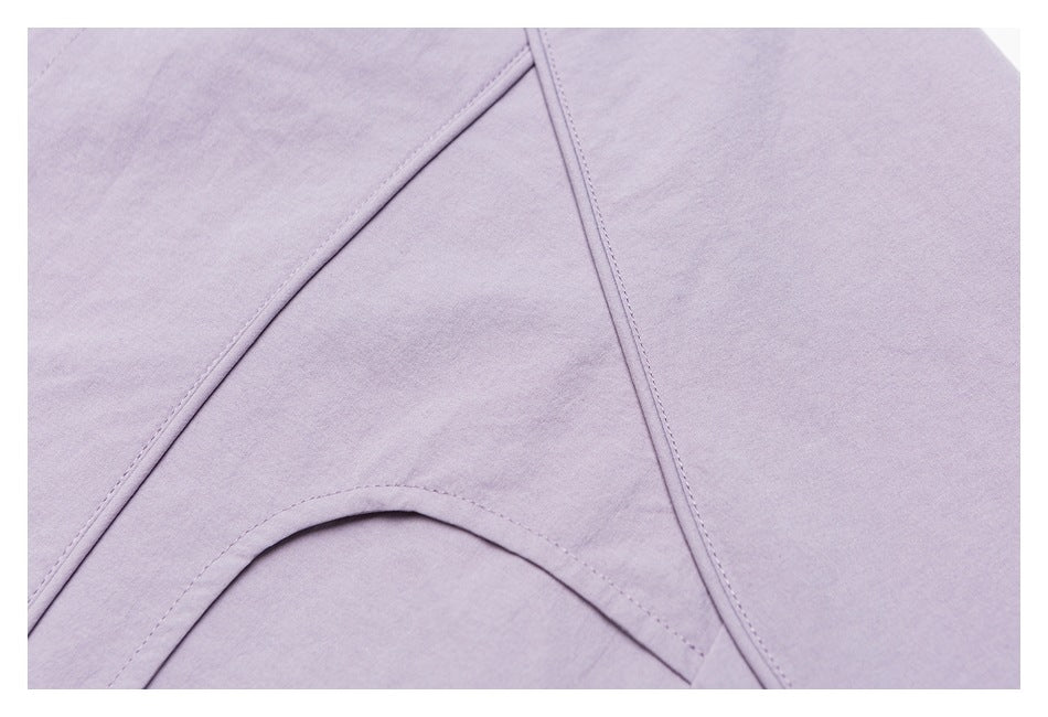 Close-up of stitched panel seams on a pale lavender shirt.