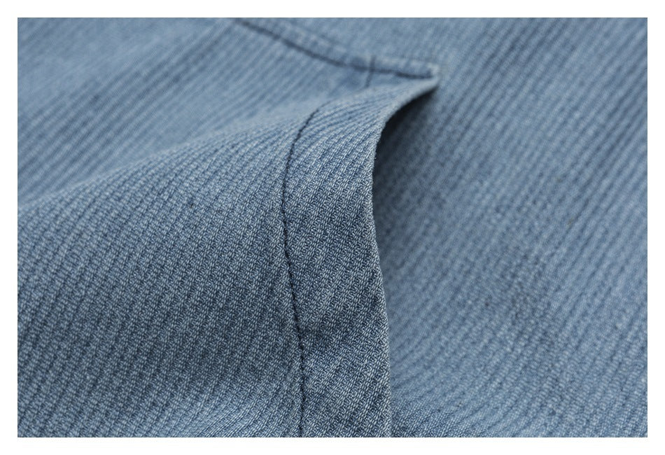 Close-up of blue-gray ribbed fabric showing a folded edge and dark stitching.