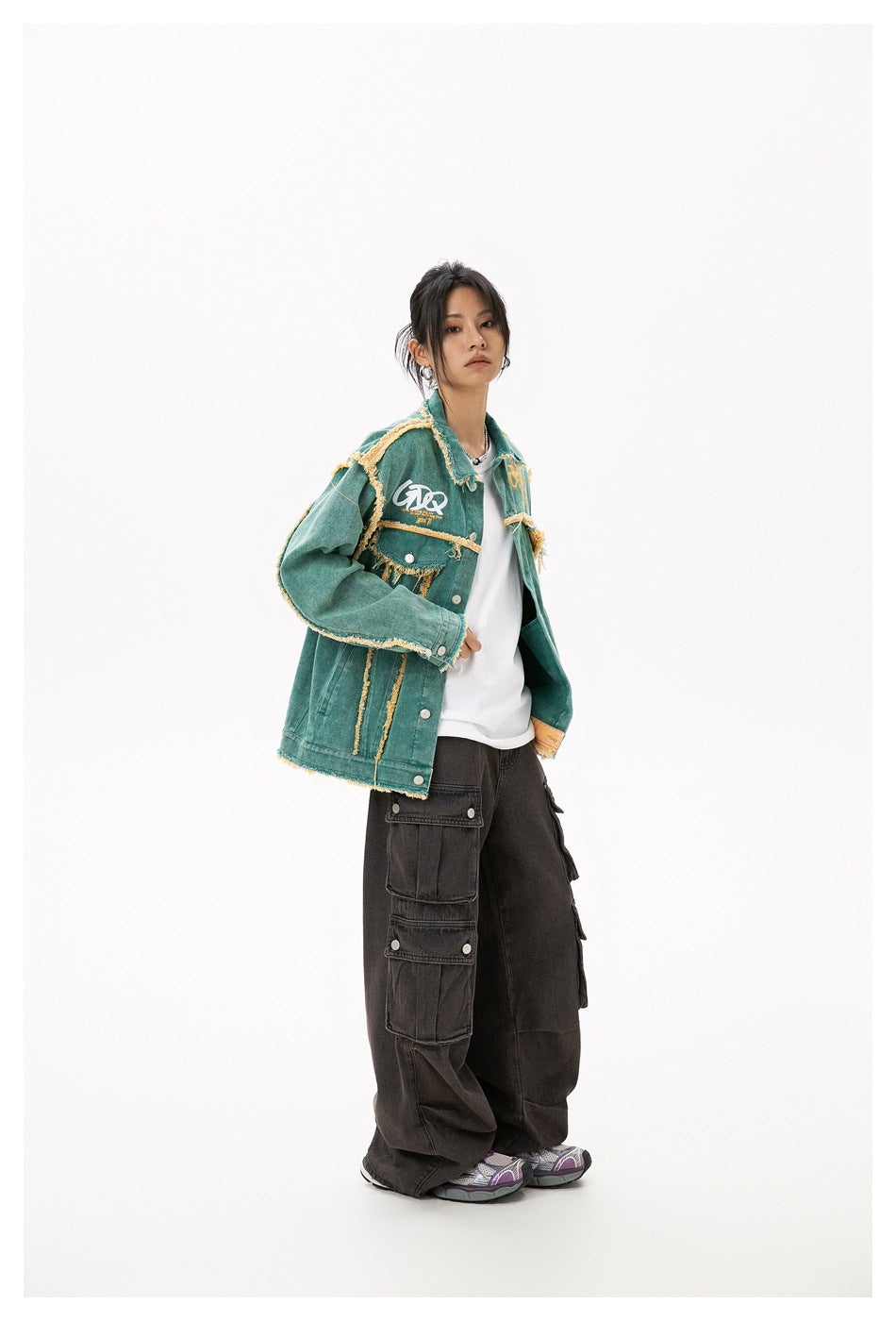 Model wearing the green frayed-edge jacket over a white tee with dark wide-leg cargo pants, shown from the side