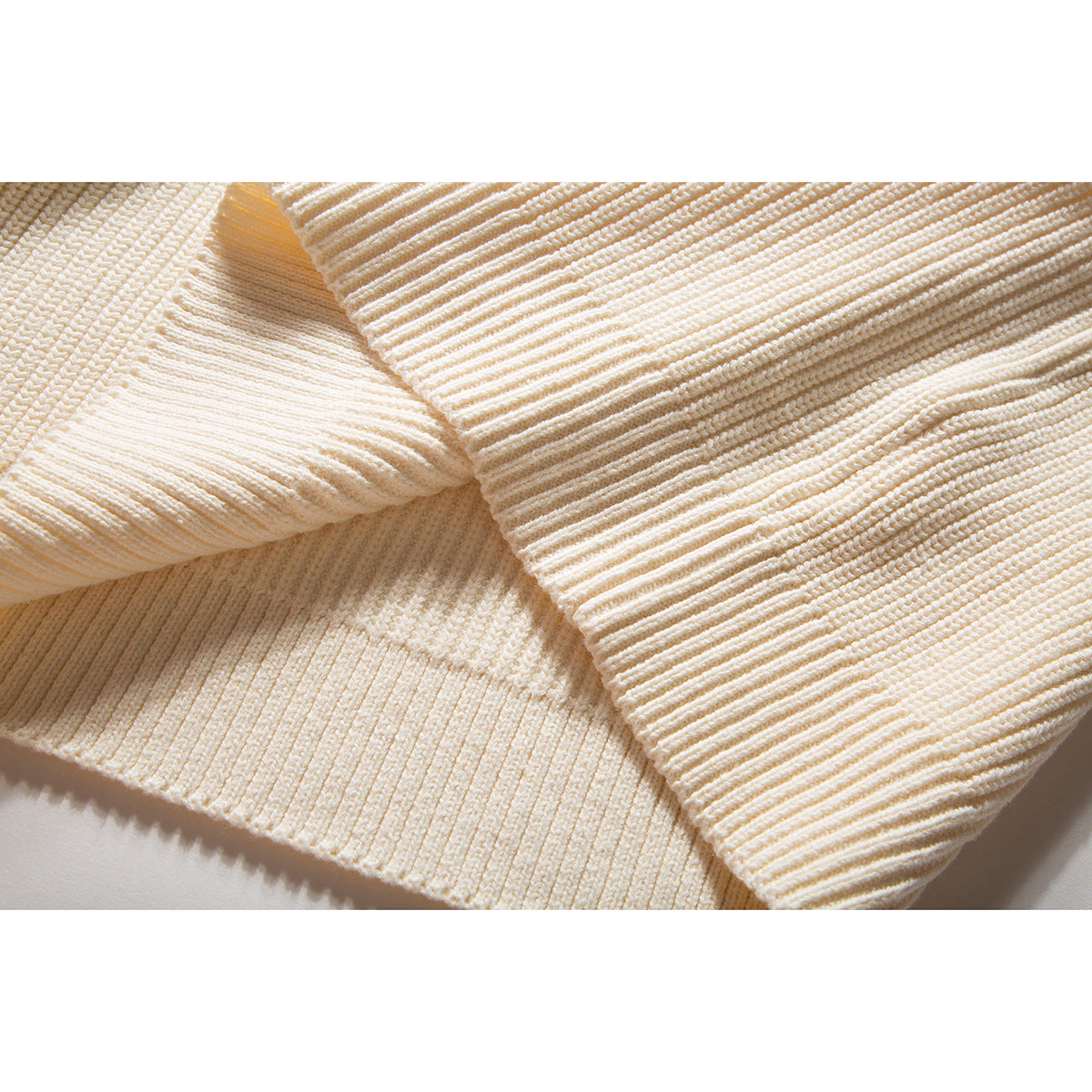 Close-up of the ivory sweater's textured knit and ribbed edge.