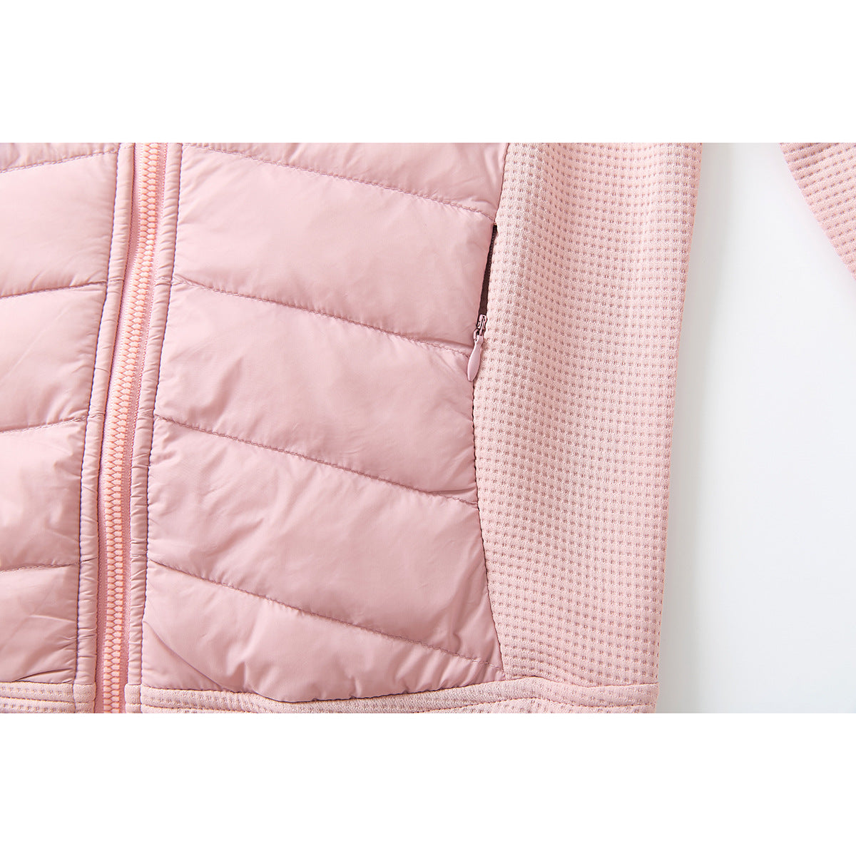 Close-up of a pink jacket's quilted front panel, zipper, textured sleeve, and side pocket zipper.