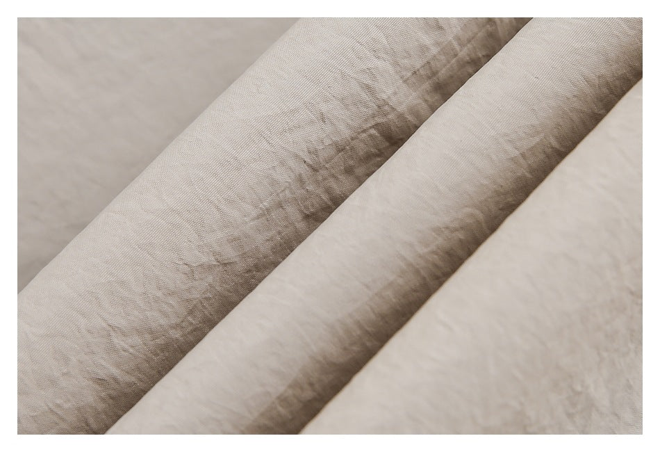 Macro view of softly wrinkled beige garment fabric showing its surface texture and folds.
