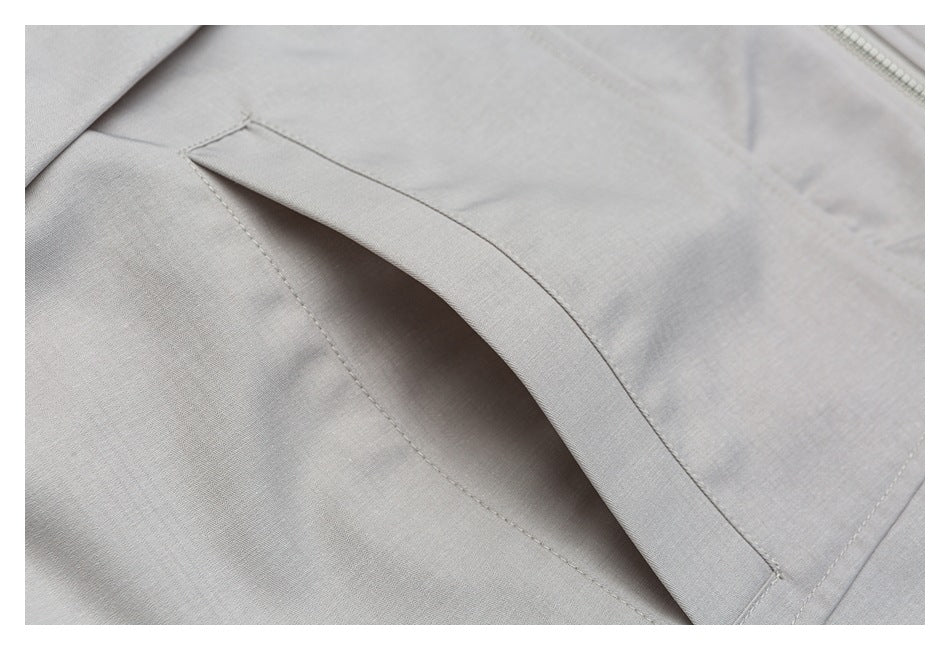Close-up of an angled welt pocket opening on pale gray fabric.
