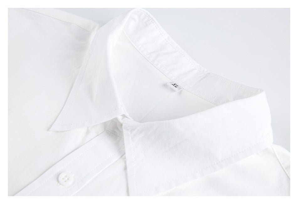 Close-up of a white shirt's pointed collar, inner label and top button.
