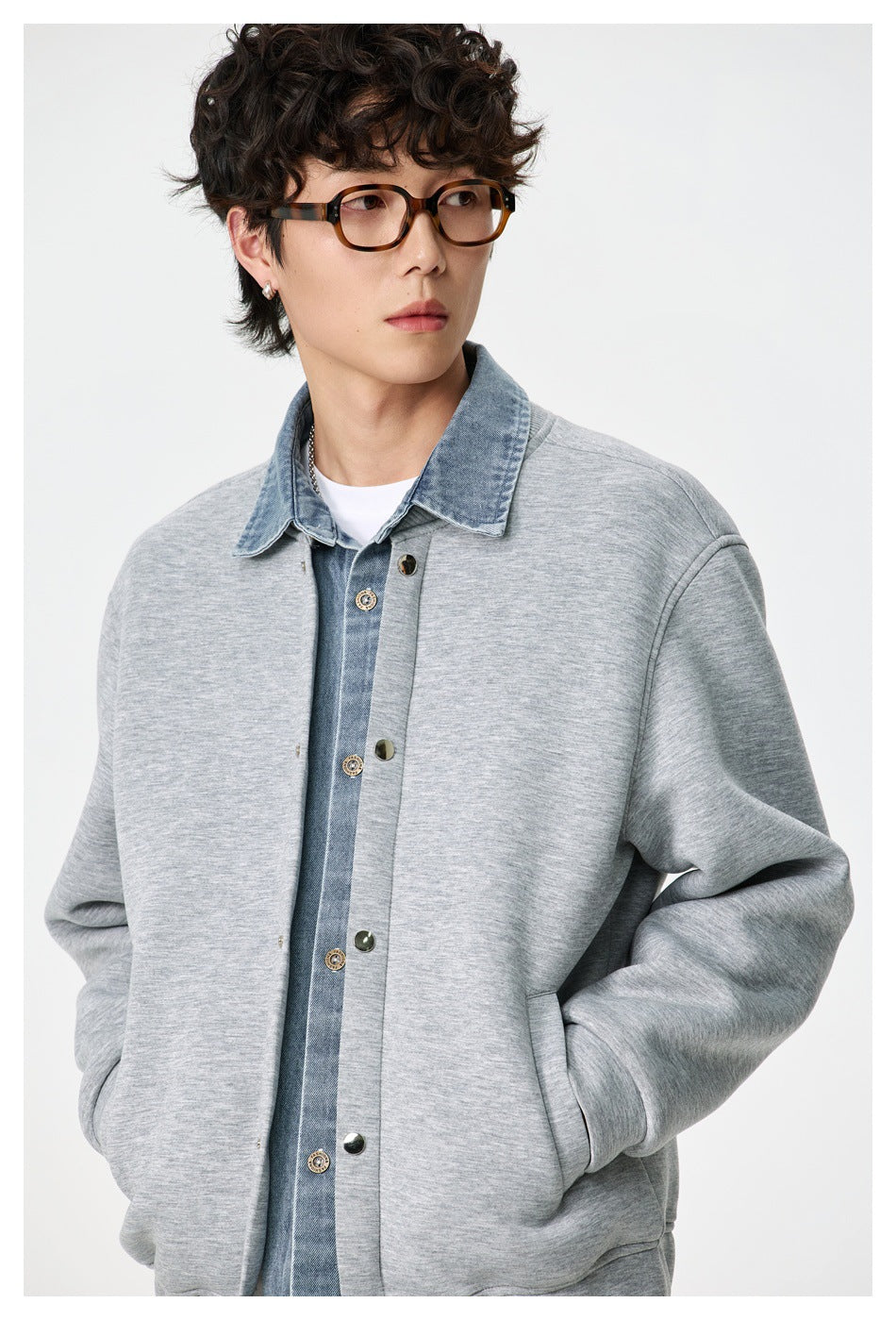 Model wearing gray jacket with denim-look collar and snap placket, close-up with hand in pocket