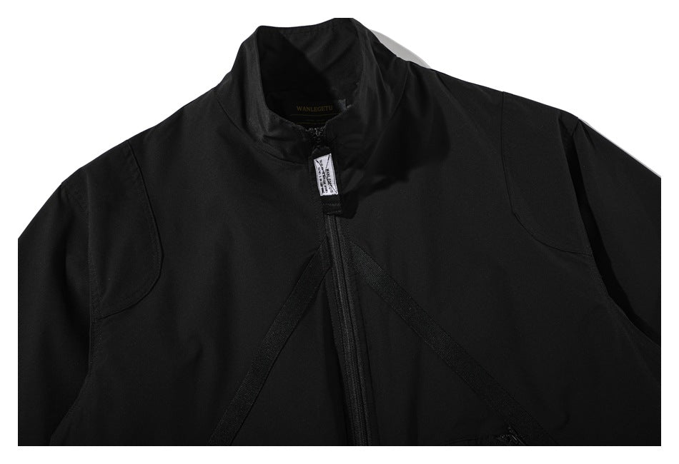 Close-up of the black jacket front, showing its high collar, central zipper, and diagonal chest straps.