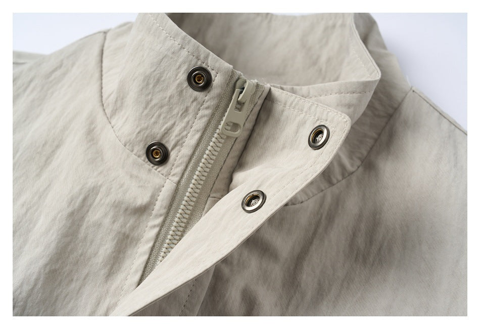 Close-up of a light beige-gray jacket collar, zipper, and metal snap fasteners.