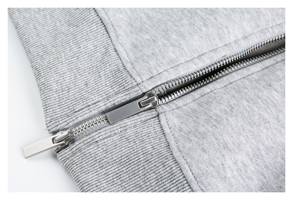 Close-up of the hoodie’s metal zipper meeting a ribbed gray waistband.