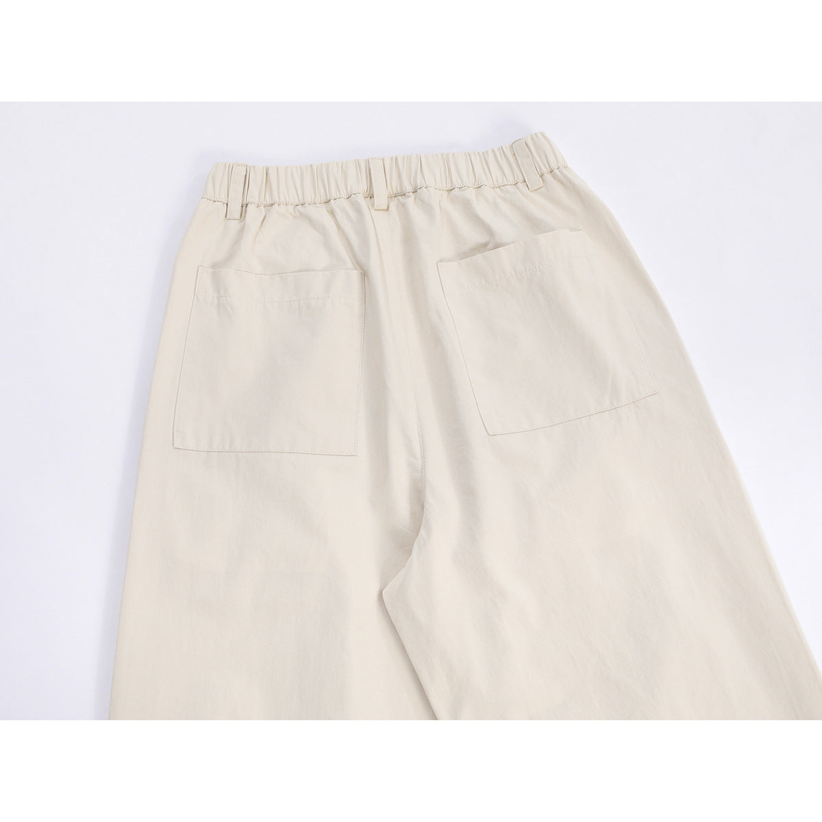 Back view of ivory wide-leg trousers with an elastic waistband, belt loops, and two patch pockets.