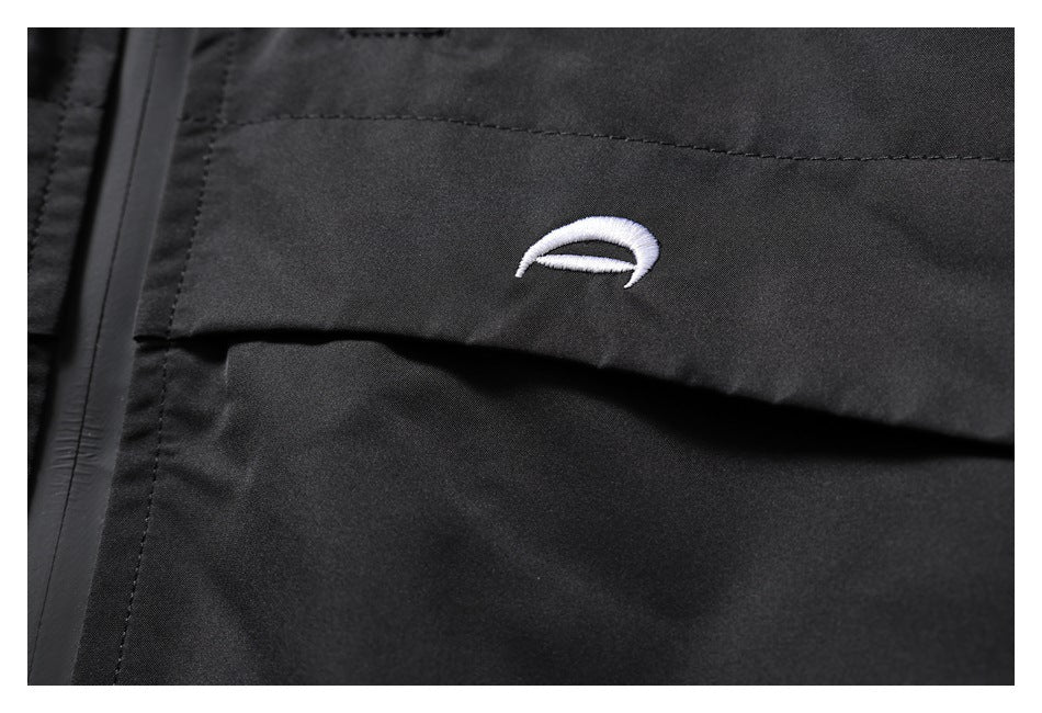Close-up of a small white embroidered curved emblem on black jacket fabric.