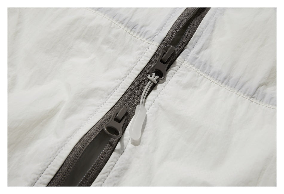 Close-up of the white jacket's dark two-way front zipper and pull tabs.
