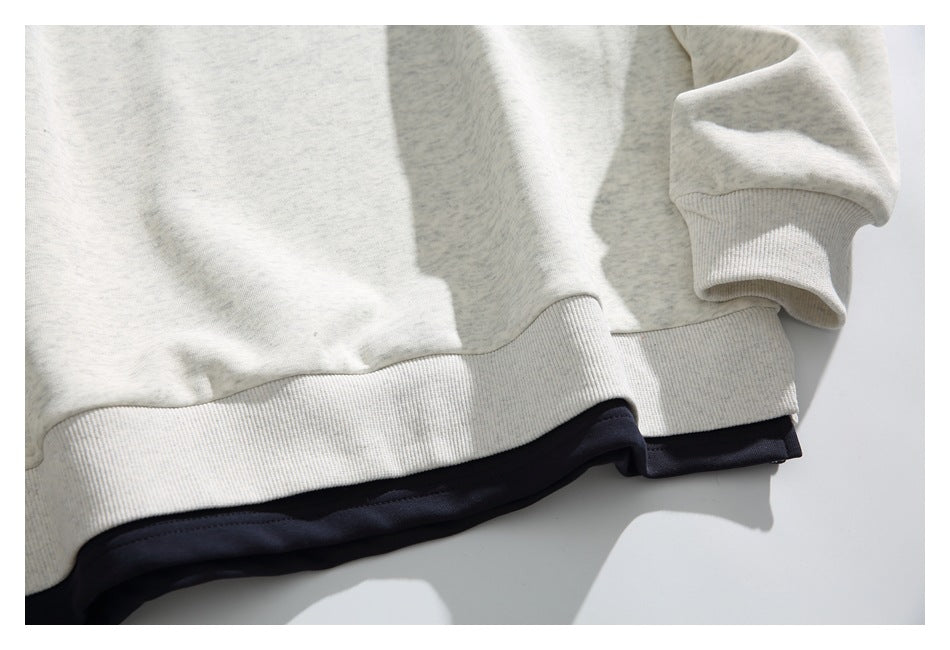 Close-up of the sweatshirt’s ribbed hem and cuff, with a dark layer visible beneath the hem.